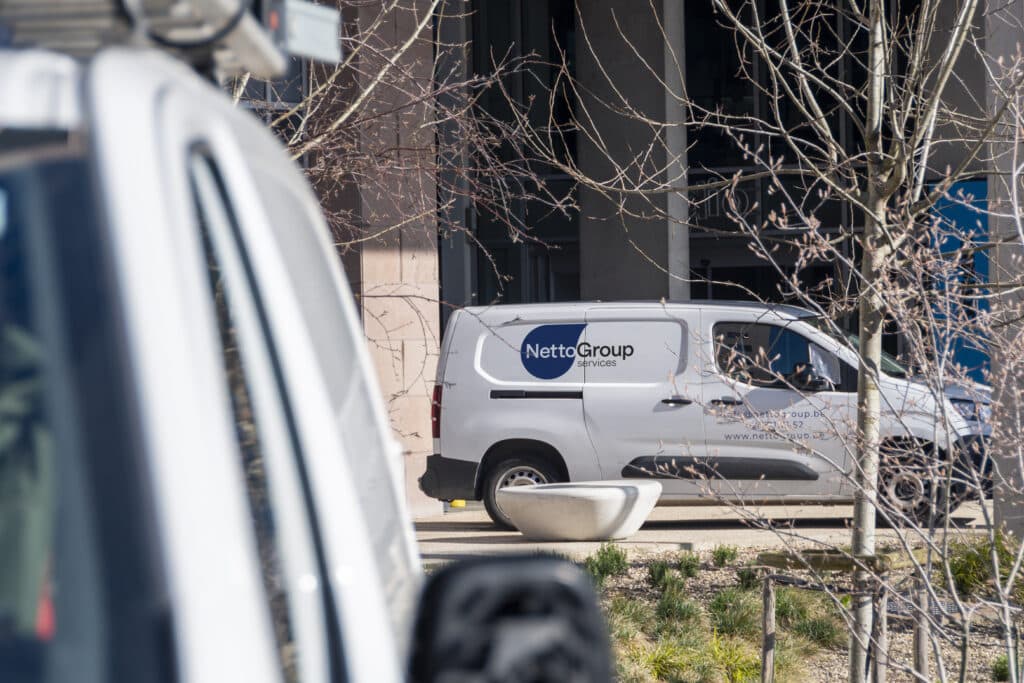 Véhicule de service Neto Group garé devant un immeuble de bureaux pour des travaux de nettoyage professionnels et la gestion des installations.