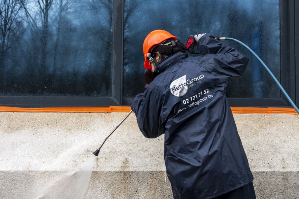 Professional façade cleaning with high-pressure sprayer by Netto Group specialist at industrial building